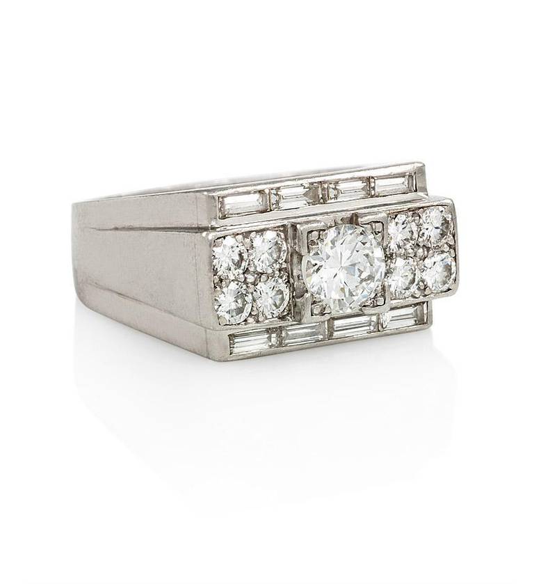 An Art Deco diamond ring featuring a geometric design centering on an old European cut diamond flanked on either side by four round diamonds, bordered by diamond baguettes, in platinum. France. 
Center stone approx. 0.81 ct. , H-I color, VS1-VS2