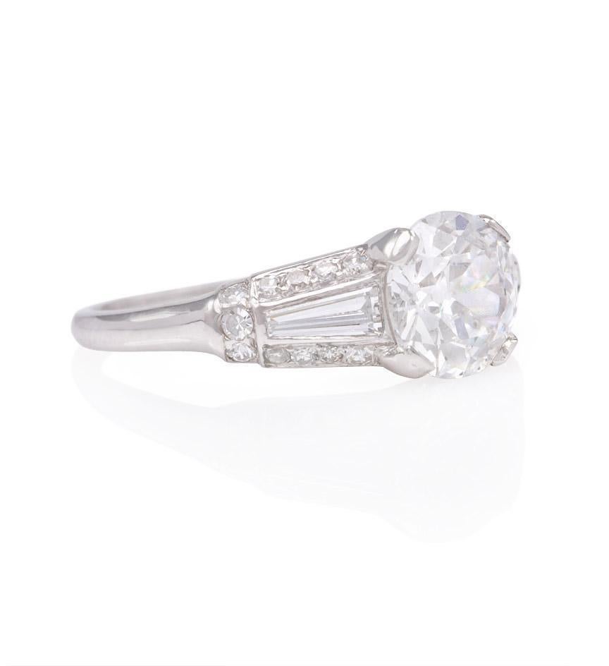 An Art Deco diamond engagement ring set with a round old European cut diamond, flanked by tapered baguettes and round single cut diamonds, in platinum.  Shreve & Co., stamped #B12135.  TW of European cut diamond = 1.61 cts., D color, SI1 clarity.