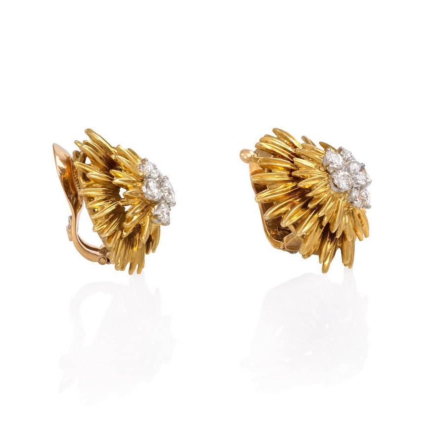 A pair of gold clip earrings of starburst design set with a central diamond cluster, in 18K and platinum. Van Cleef & Arpels, France. #15032.