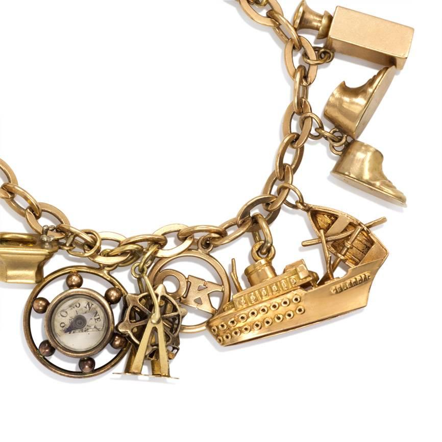 A Retro gold charm bracelet comprised of twenty predominantly French charms including a compass, a globe, ship's lanterns, a cruiseliner, binoculars, the evening news, a sink, a gondola and others, in 18k and 14k.  One 14k gold 