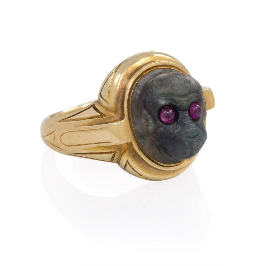 An antique gold ring set with a carved labradorite depicting a monkey head with ruby eyes, in 18k.  England.  (Top of ring measures 17mm high.)