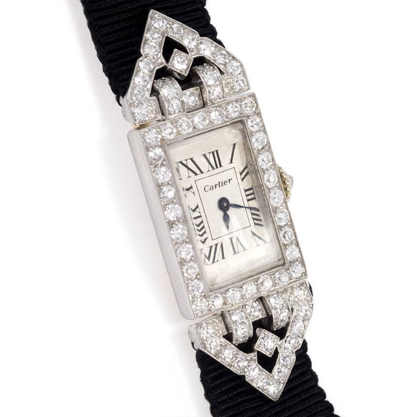 An Art Deco diamond watch with a rectangular face flanked by triangular openwork flanges, with a deployante clasp on a leather-backed grosgrain strap, in platinum and 18k gold. Cartier, Paris.  Atw diamonds 0.75 ct.