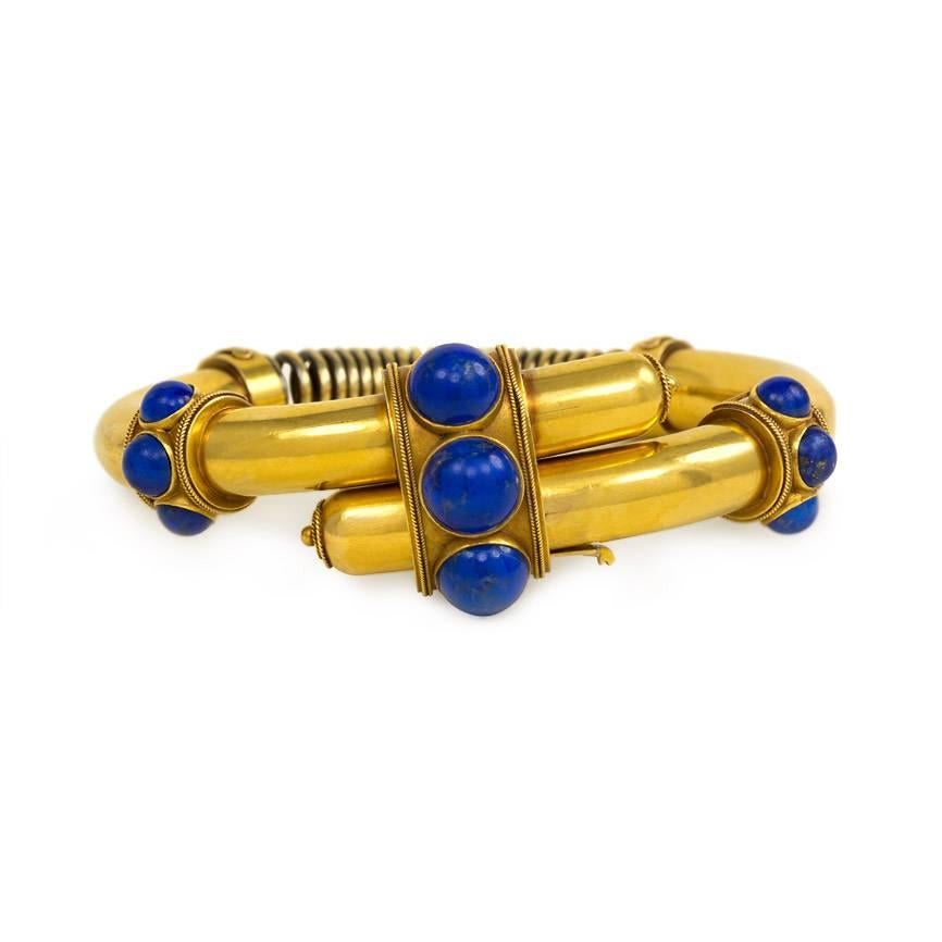 An antique gold bracelet of bypass design featuring three banded segments set with lapis, with coiled spring back, in 18k.

6.5