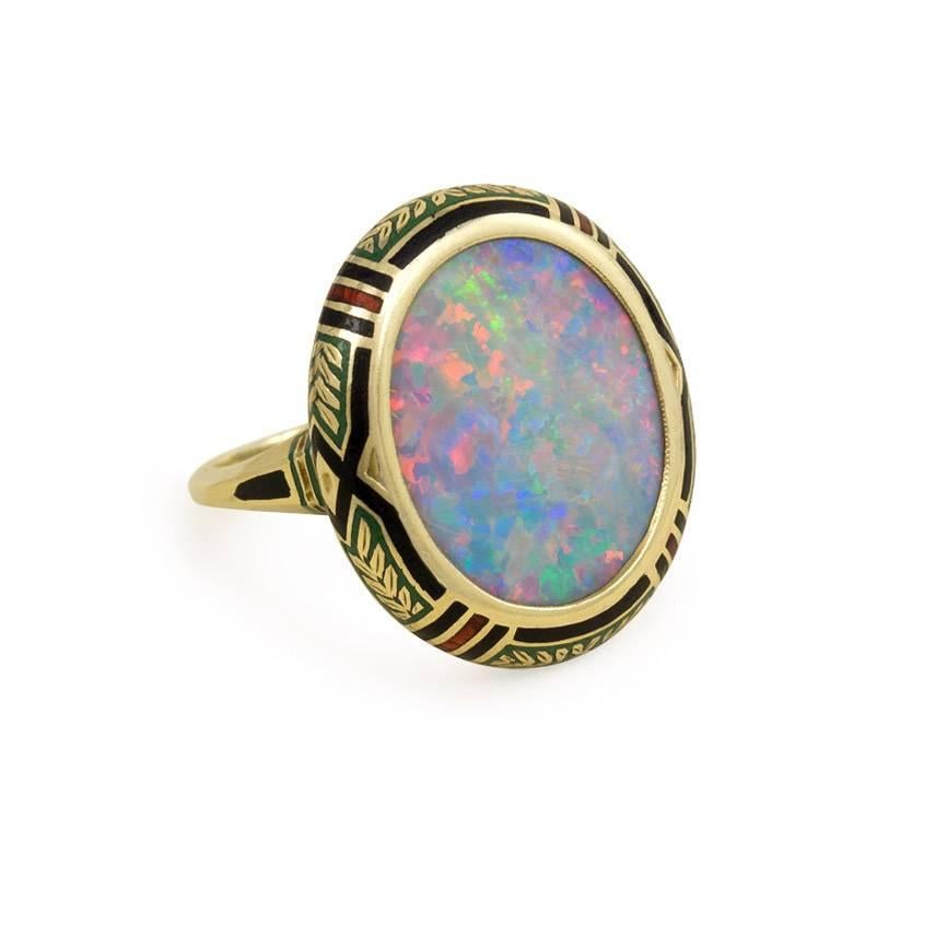 An antique gold ring in the Arts and Crafts style comprised of an oval opal in a multicolored enameled setting, in 14k.

Top measures approx. 7/8 x 5/8