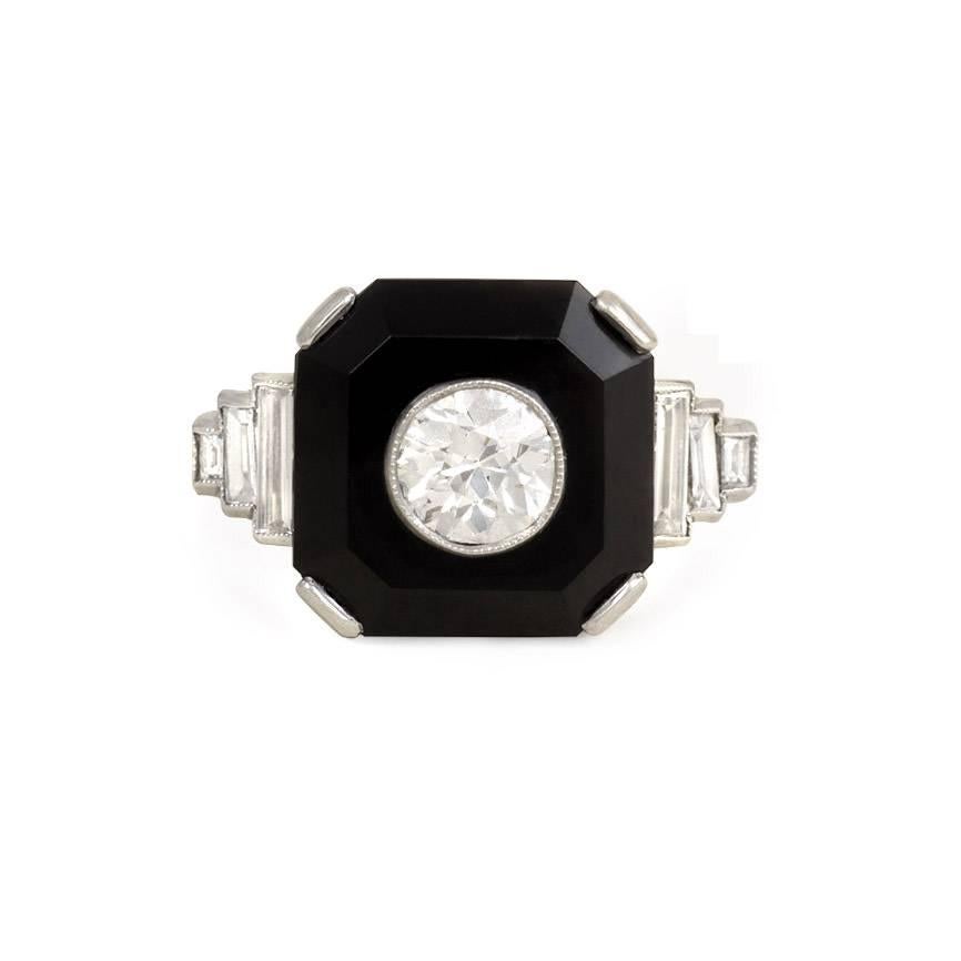 An Art Deco ring comprised of an octagonal onyx plaque set with an old European cut diamond and flanked by stepped baguette cut diamond shoulders, in platinum.  Center stone approximately 0.67 tw. 