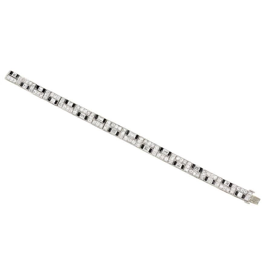 An Art Deco diamond and onyx bracelet set with round and step cut diamonds in a geometric pattern; each step cut diamond flanked by French cut onyx, in platinum.  Udall & Ballou. Atw. 7.00 ct. diamonds.