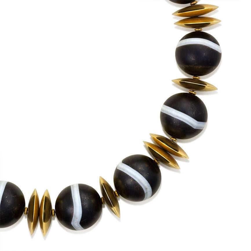 A large banded agate bead necklace comprising 25mm beads with gold disc spacers, in 18k.  239.80dwt, 372.9g.