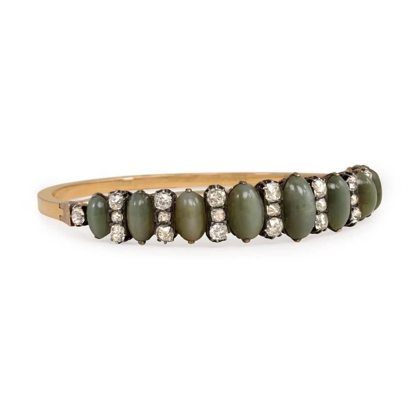 An antique half-hoop bracelet of alternating cat's eye quartz and old-mine-cut diamonds, in sterling silver and 18k gold. French import marks

6 1/2in. inner circumference, 7/16in. widest point