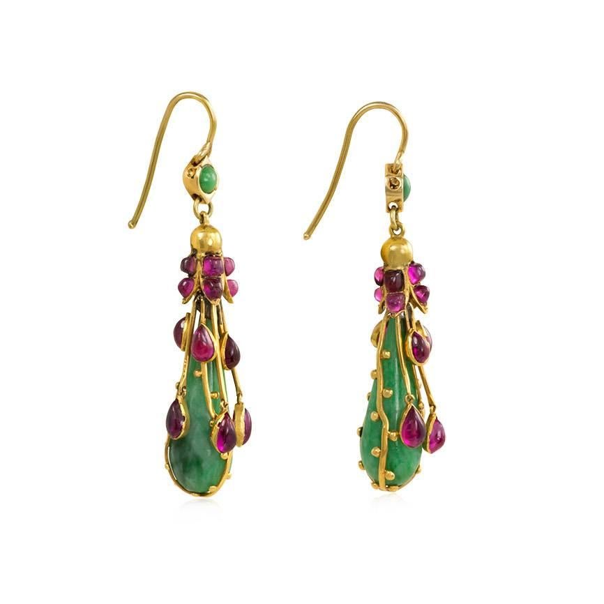 A pair of Art Nouveau gold, jade, and ruby earrings, the pear-shaped jade pendants suspending from gold foliate and cabochon ruby caps and decorated with gold wire and articulated cabochon ruby drops, in 15k.  England, Dutch import