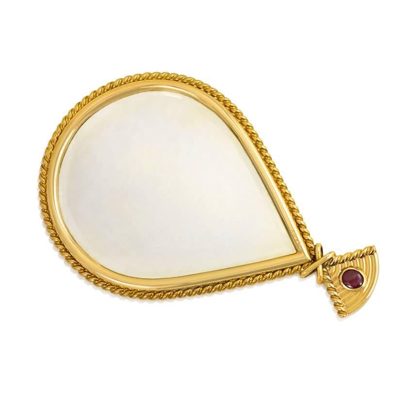 A Retro gold fan-shaped hand mirror with engraved design and twisted borders, set with a cabochon ruby, in 18k. Cartier, #2873. Original silk fitted case.