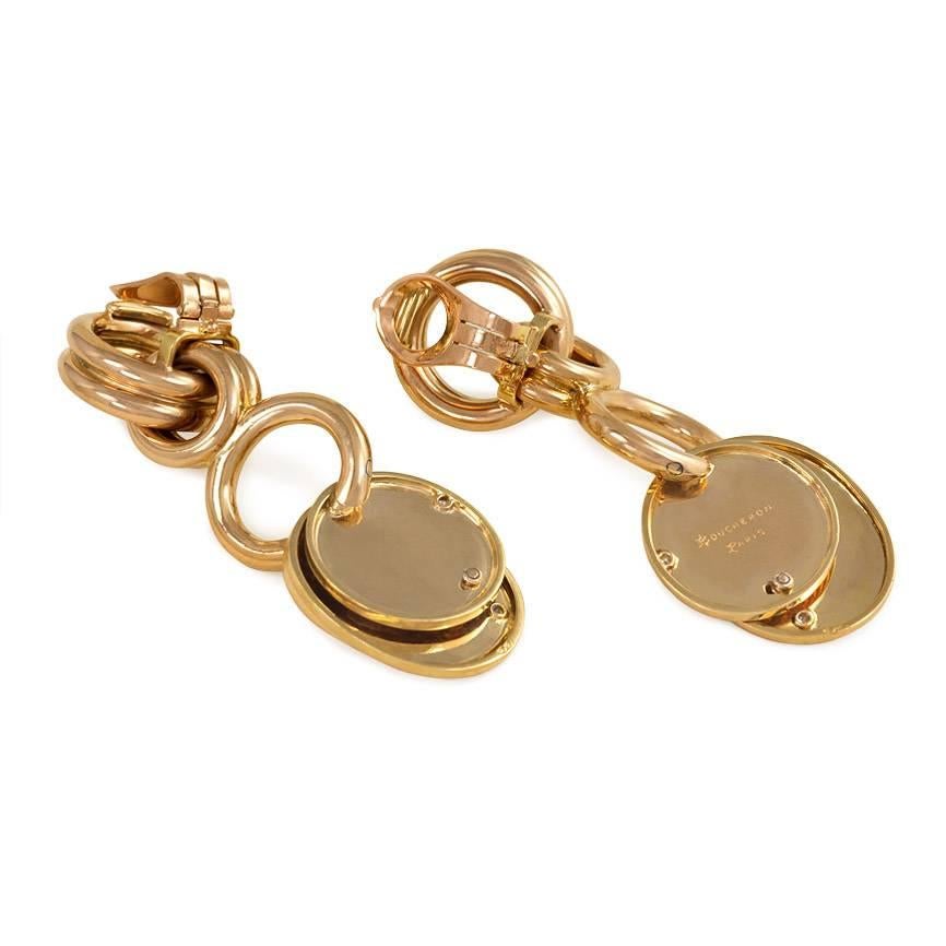 A pair of Retro gold earrings designed as interlocking rings suspending articulated disc-shaped pendants embellished with star-set diamonds, in 18k.  Boucheron, Paris