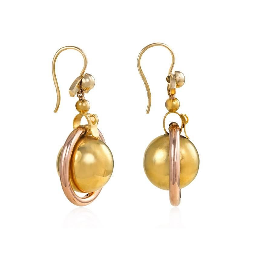 A pair of antique two-color gold earrings with ball pendants in rose gold hoops, surmounted by buckle motifs, in 14k. Russia