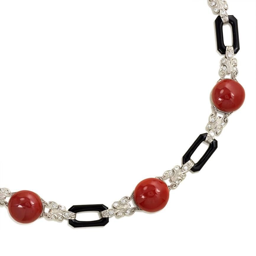 An Art Deco necklace of carved onyx links and engraved, diamond-set links with oxblood coral cabochons, in platinum.

Dimensions: 15 3/8" long, 7/16 - 9/16" wide