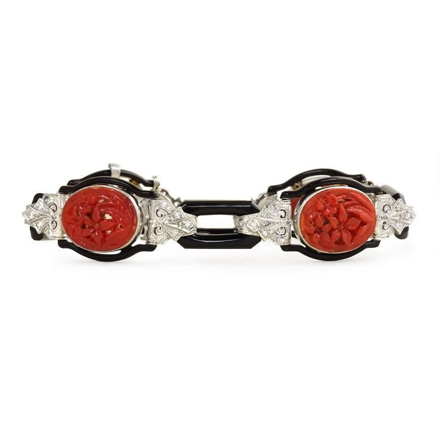 An Art Deco bracelet comprised of carved onyx links and surrounds with engraved diamond set links and oval carved coral panels of foliate design, in platinum. Atw. 0.40 ct. single cut diamonds.