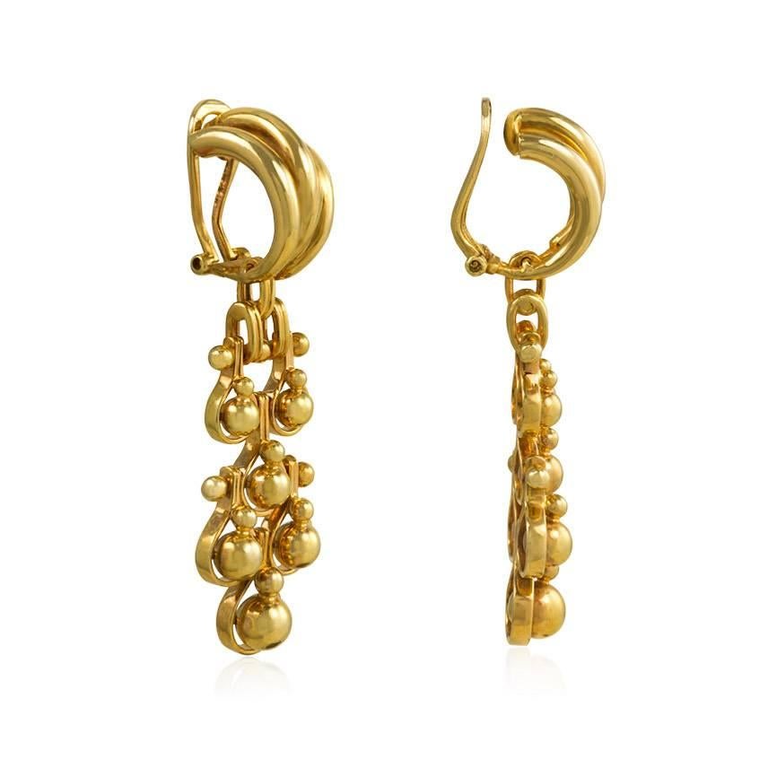 A pair of Retro gold earrings comprised of articulated ball pendants descending from ribbed half-hoop surmounts, in 18k.