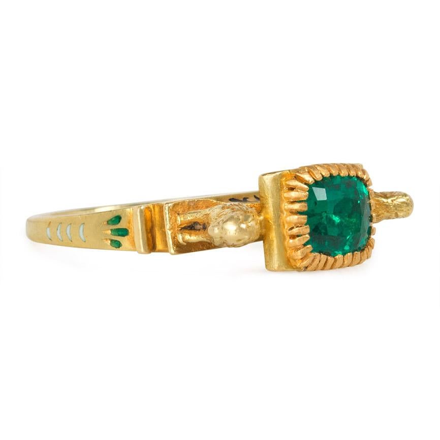 An antique Egyptian Revival ring centering on a cushion-shaped emerald in a pedestal-form mount, flanked by lions, in 18k gold with scrolled shoulders and multicolored enamelled accents.  France

Dimensions: Sits 11mm above hand, top measures