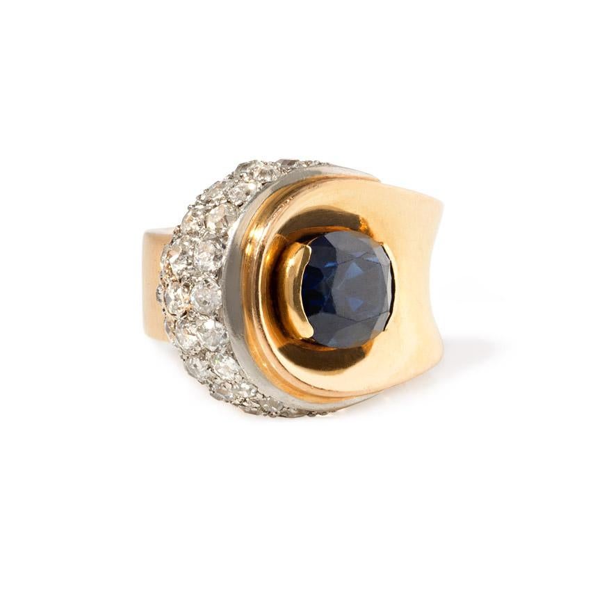 A Retro gold ring of buttoned design centering on an oval sapphire with a pavé diamond segment, in 18k and platinum.  Sapphire approx. 3.16 cts.; atw diamonds 1.50 ct.  France

Current size: 5
5/8