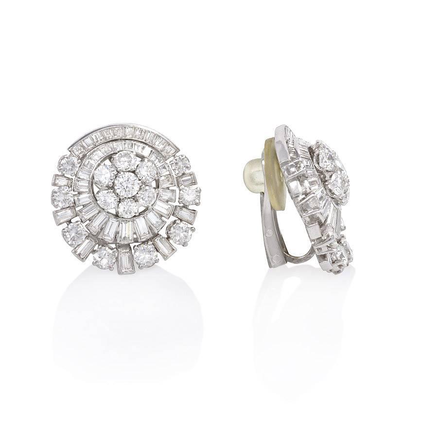 A pair of diamond clip earrings of circular radiating design with cluster centers, in platinum. France.  Atw 3.60 cts.