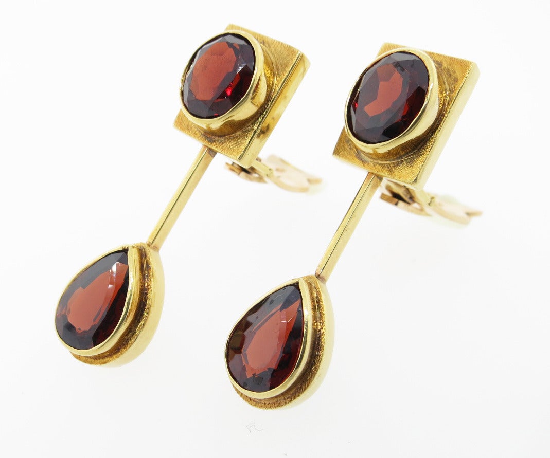 Handmade 18kt. brushed yellow gold garnet drop earrings by the Brazilian designer Burle Marx. Each earring measures 1 1/2 inches and is bezel set at the top with an oval faceted natural garnet each  weighing approx 1.9 with a pear shape garnet drop