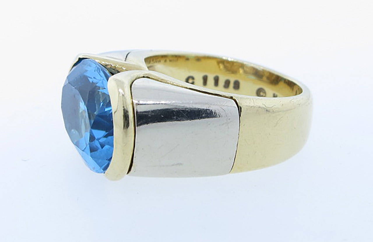 18kt. yellow and white gold Marina B. vibrant blue topaz ring .  The center is half bezel set with an oval faceted topaz measuring 13.1 X 10 X  6.5 mm.. weighing approx 6 cts. The ring is size 5 1/2 and can be sized.Signed.