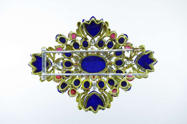 Well constructed front and back the dimensional design  brooch is handcrafted in 18kt yellow gold. The lapis lazuli are a mix of  cabochon and carved,  spaced with 16 round cabochon natural rubies and accented by 24 round diamonds set in white gold