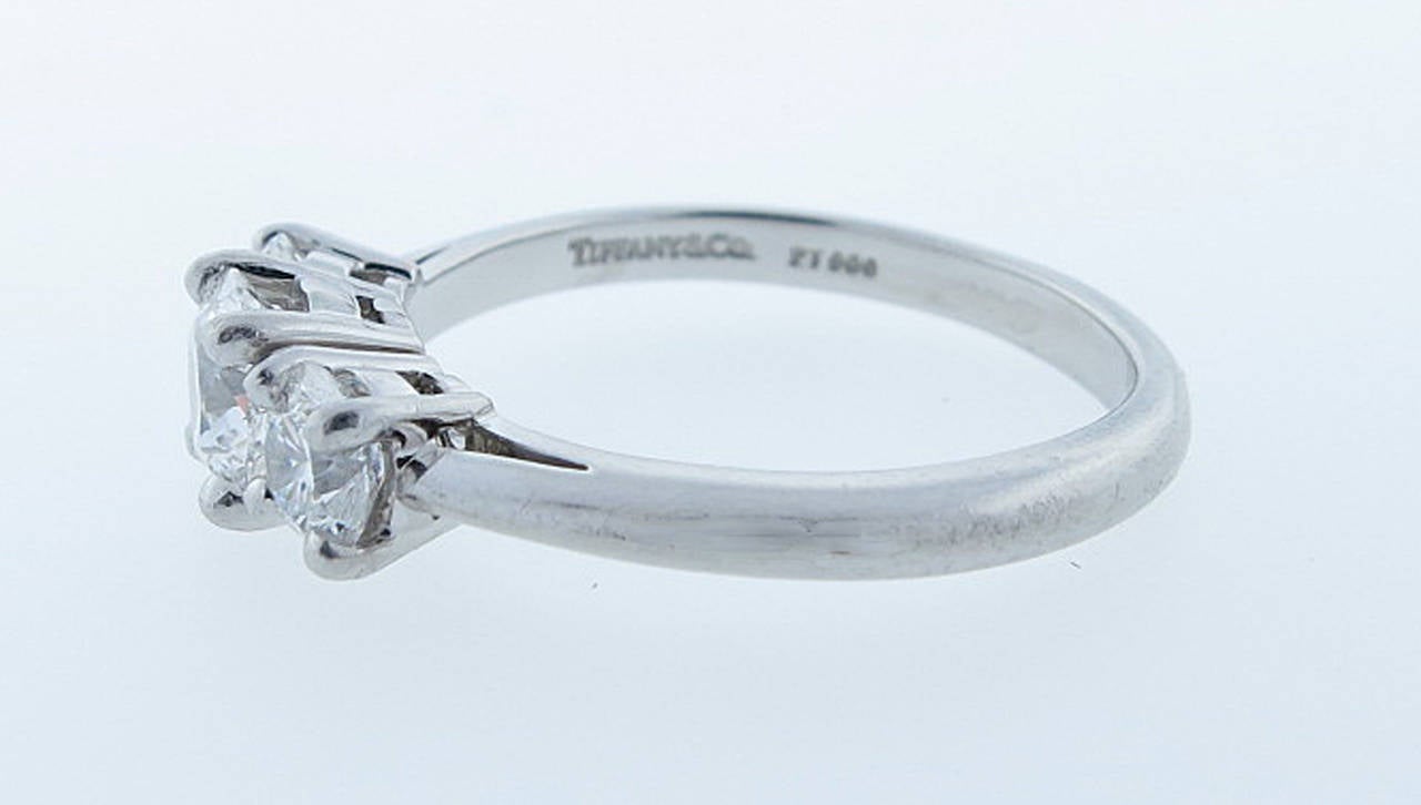 Platinum mount Tiffany & Co. diamond three stone ring. The center round brilliant cut diamond weighs .75cts grading E color VVS1 clarity, one side diamond weighs .33cts. grading E color VVS1 clarity, and the other weighing .34cts. grading E color