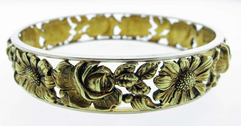 Intricately carved French 18kt yellow gold slip on bangle in a high relief ornate floral design. The edges are banded in white gold .The bracelet measures approx 8 1/4