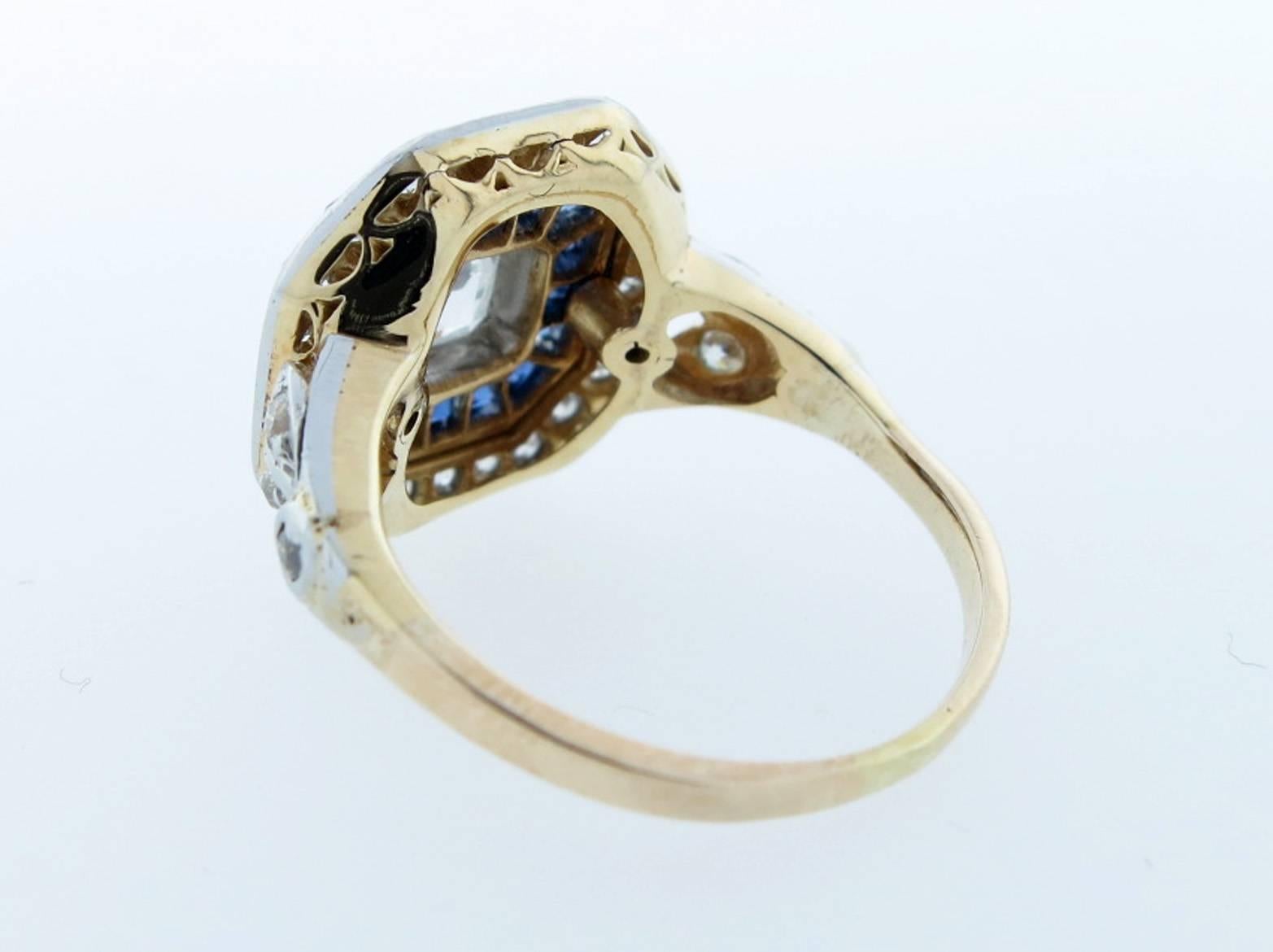 Stunning regal platinum top and 18kt. yellow gold ring. Bezel set with a center old Asscher cut diamond weighing approx .80cts. grading VS clarity H color  surrounded by 16 tapered faceted natural blue sapphires. The frame is bead set with 30 old