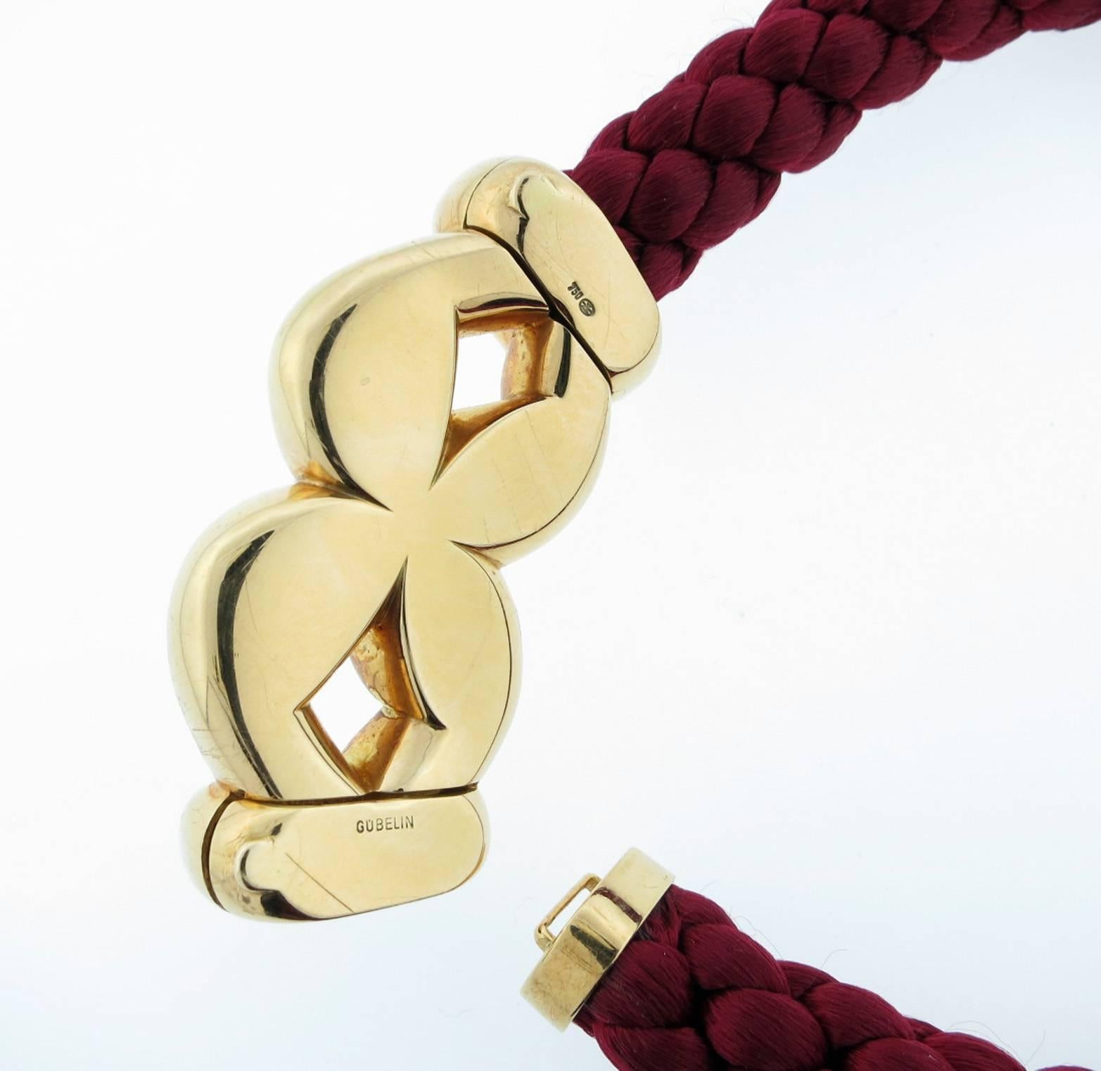 Elegant 18kt yellow gold knot front necklace made by the Swiss jeweler Gueblin. The necklace measures 16 inches in length and the rich garnet braided silk cord measures 13 mm. wide. Hidden catchs on each side at the back Signed. 