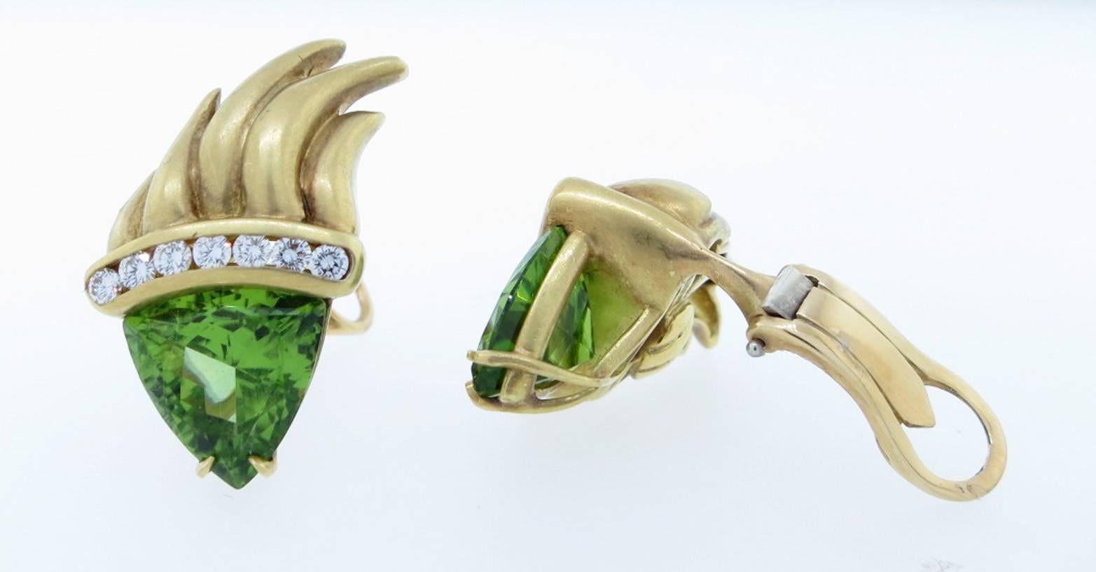 Opposing flame design 18kt. yellow gold earrings. Each clip-back earring is prong set with a triangular shape fine color natural peridot each weighing approx 4.5cts. The top of each is channel set with seven round brilliant cut diamonds totaling