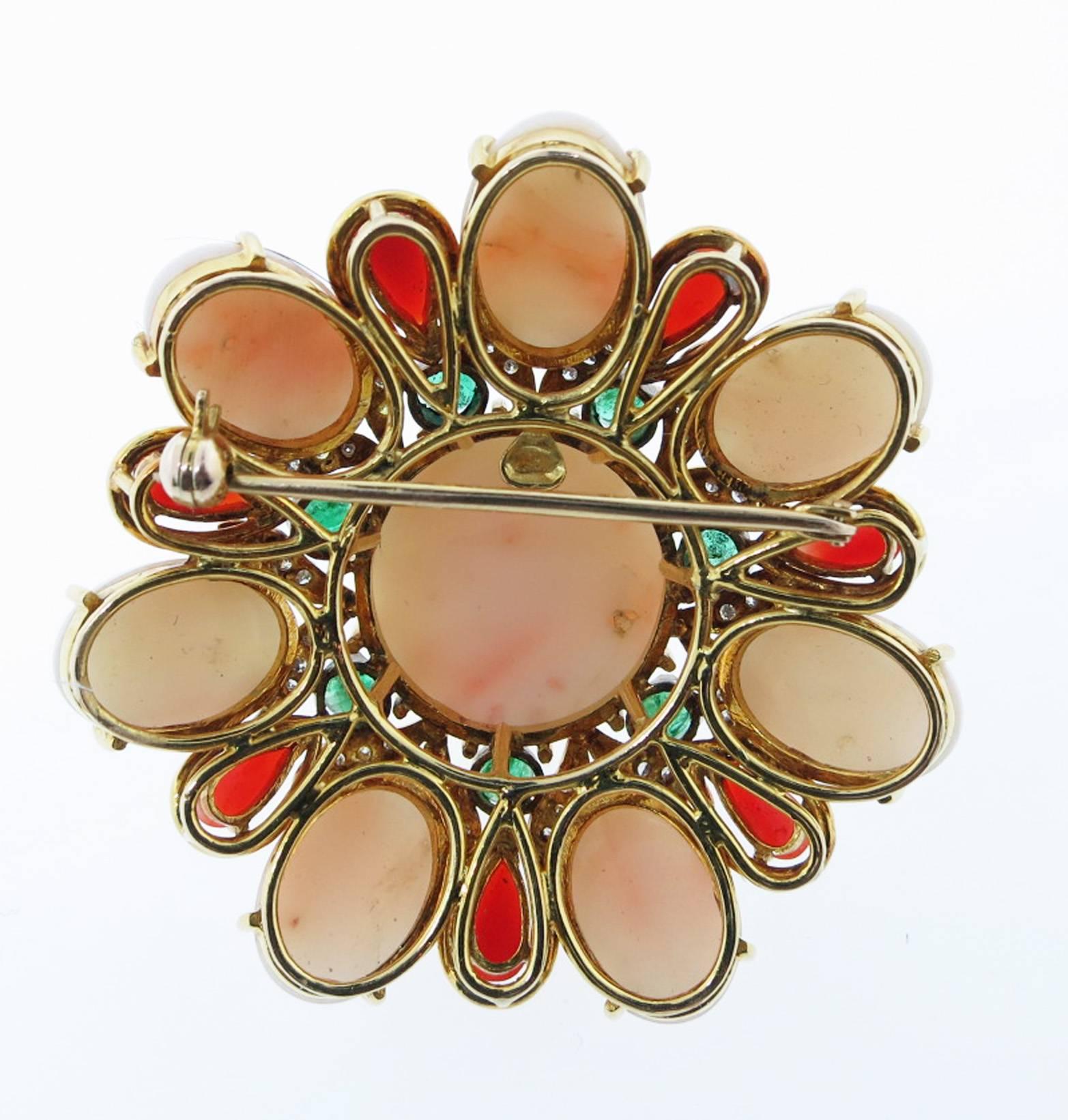 18kt. handmade yellow gold mount brooch. The center is set with a cabachon angel skin coral measuring 19mm. surrounded with seven faceted natural emeralds totaling approx .1.2cts., seven marquise shape rich oxblood corals and seven oval angel skin