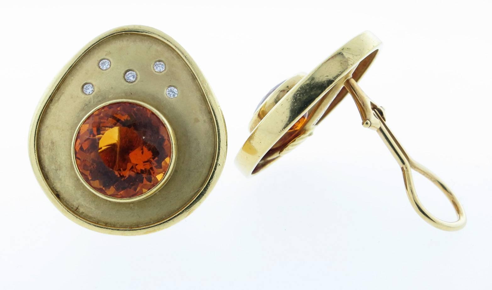 Free form 18kt. yellow gold,  two finish earrings made by Susan Sadler. Each earring measures approx. one inch and is bezel set with a faceted golden citrine weighing approx. 5.0 cts and five round brilliant cut diamonds. Clip back and posts can be