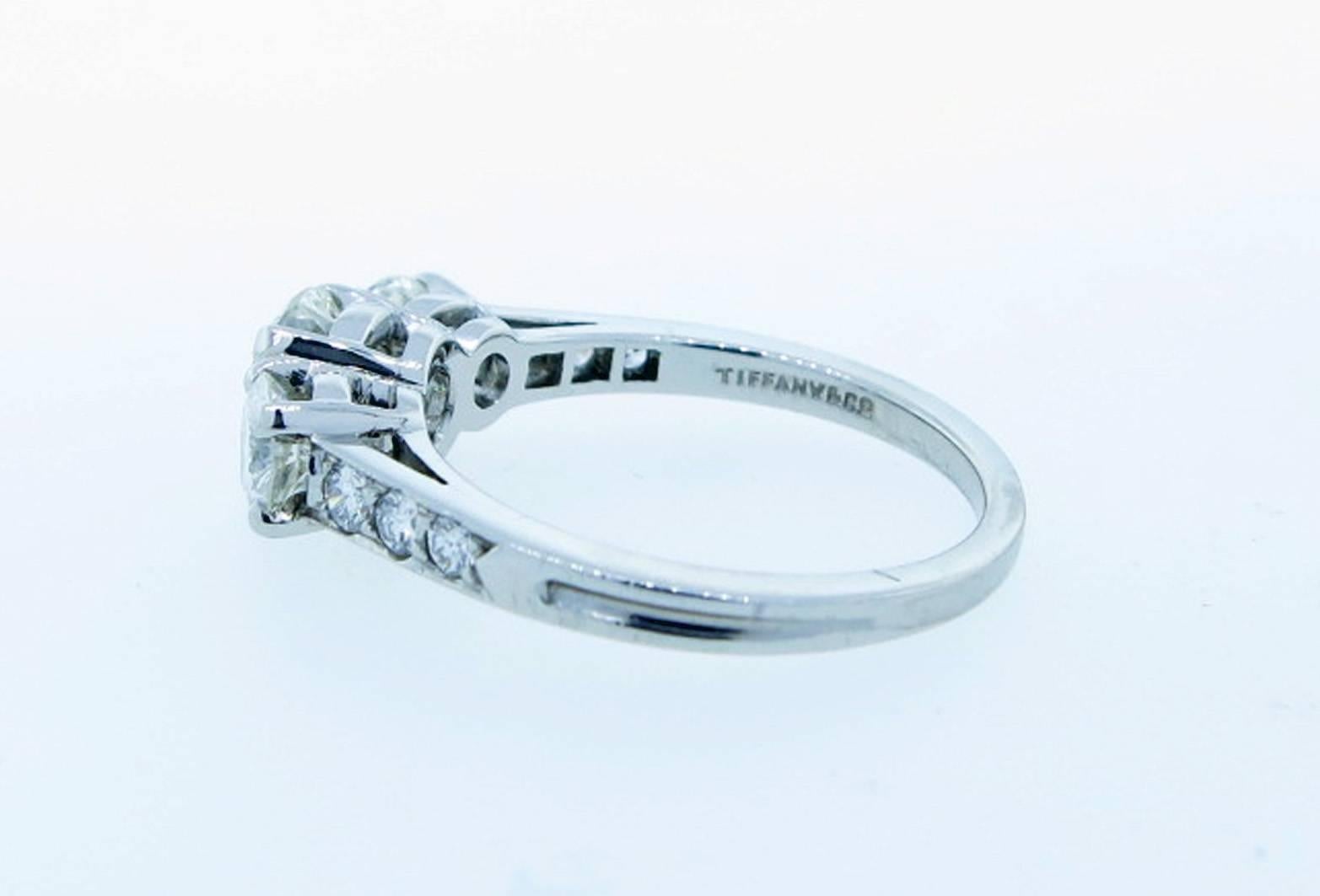 Timeless design Tiffany three stone diamond ring prong set in platinum with a center round brilliant cut diamond weighing approx .70cts. with a prong set diamond on each side, total diamond weight approx 1.25cts. Each side of the shank is bead set