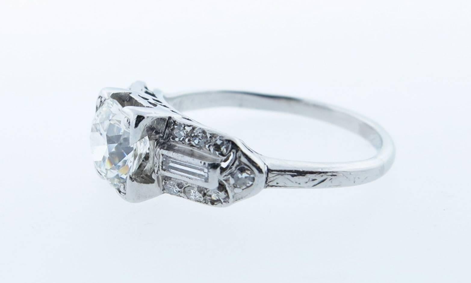 Handmade platinum mount 1.0 ct center round European cut diamond ring grading VS clarity H-I color.The lovely engraved open work mount is bead set on each side with a baguette and seven round old cut diamonds totaling approx  .25cts. Size 5 and can