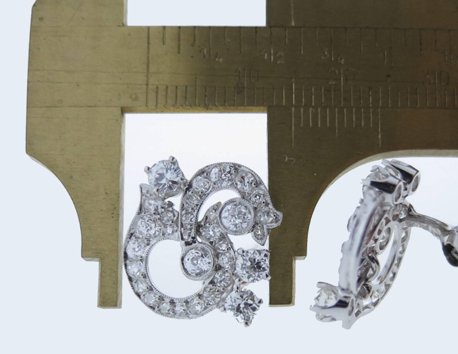 Handmade opposing swirl design platinum mount diamond earrings. Each earring measures approx .75 inches in length and is bezel and prong set with five old mine cut diamonds totaling approx .40cts. The surrounding mount is bead set with 25 old mine