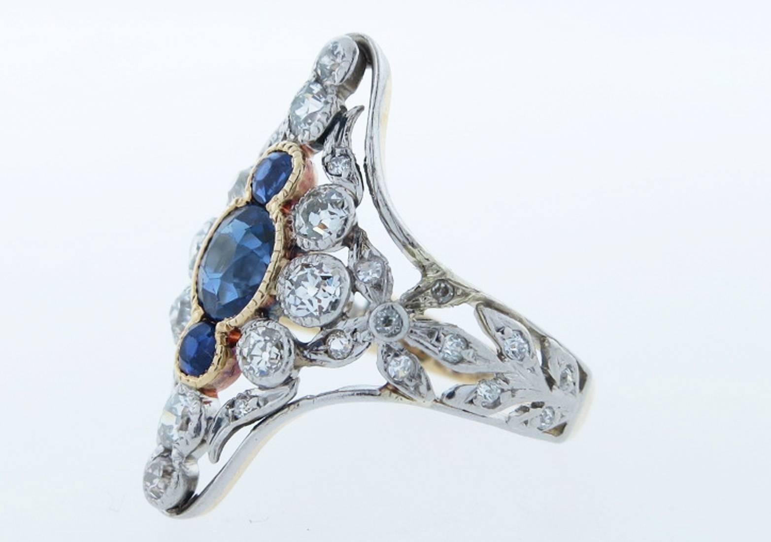 Radiant handmade platinum top and 18kt yellow gold back Edwardian dinner style ring. The center is set in yellow gold with three natural faceted fine blue sapphires totaling approx .80cts. The mount is bead and bezel set with thirty four old cut