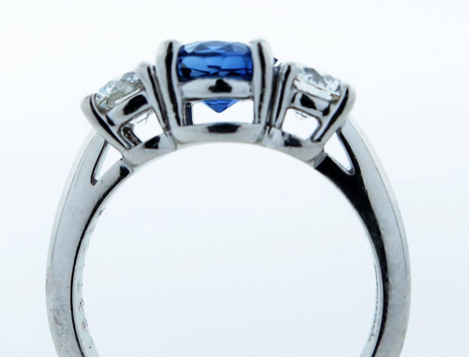 Tiffany & Co. three stone platinum mount sapphire and diamond ring. The center is prong set with a gem color natural round faceted blue sapphire weighing approx 1.25cts. Each side is set with a twinkling round brilliant cut diamond each weighing