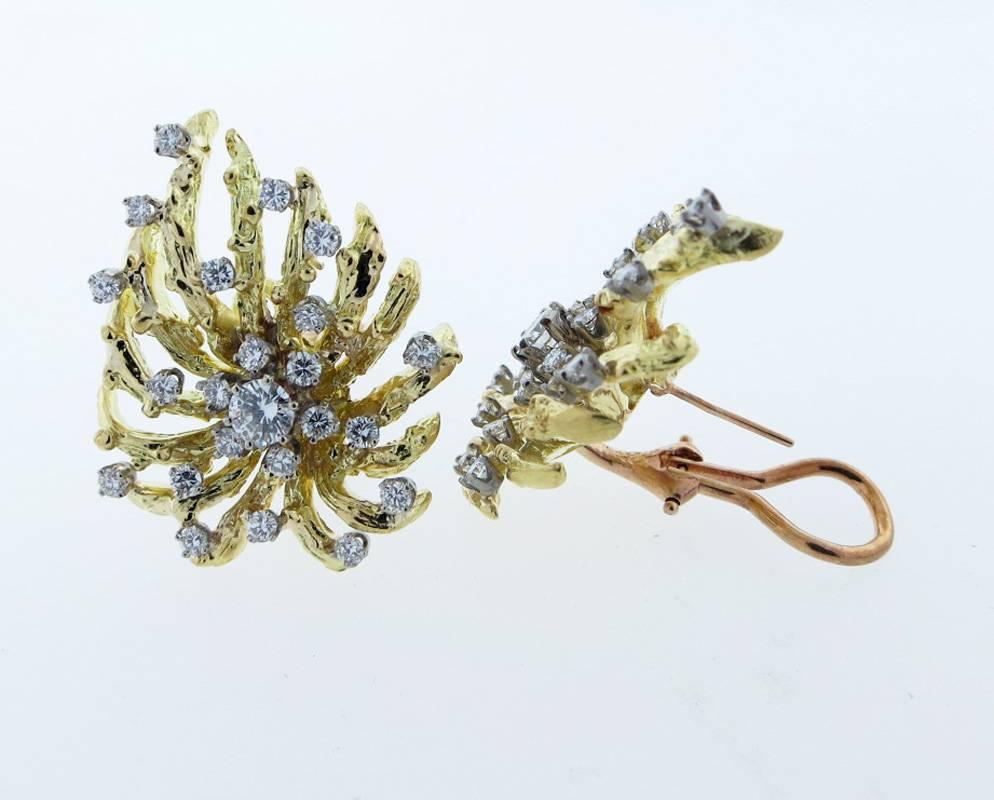 Opposing design clip and post back earrings in 18kt. yellow gold  Each earring measures approx 1.25 inches in length and are prong set with 23 round brilliant cut diamonds totaling approx 1.0cts. The diamonds grade Vs clarity G-H  color. 