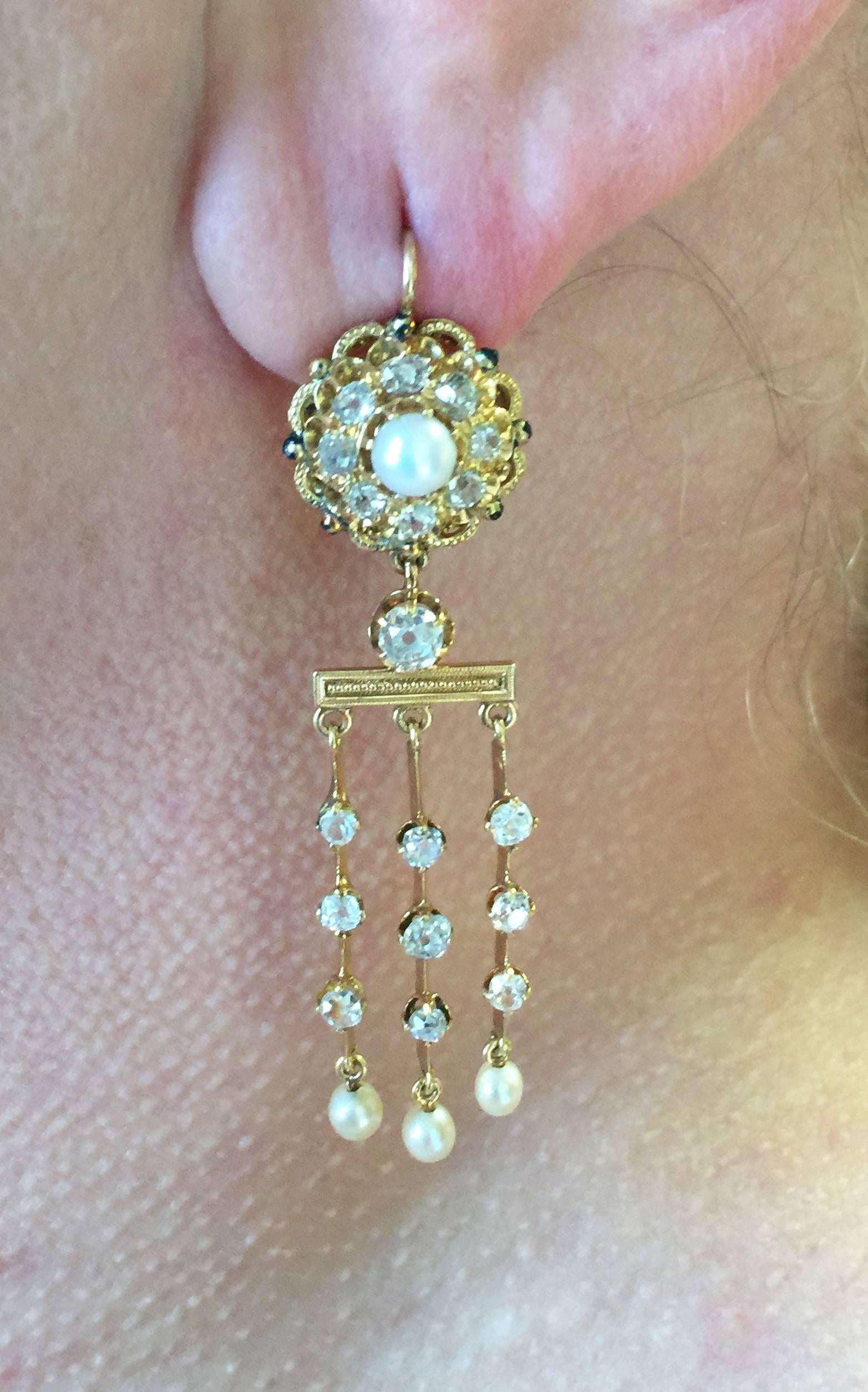 Lovely 18kt. yellow gold diamond and pearl dangle earrings. Each handmade earring measures approx 2.5 inches in length and is set at the top with a cluster of eight old mine cut diamonds with a fine natural 5.0mm. pearl center with black enamel