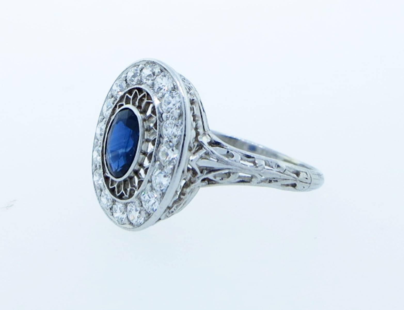Exquisite antique Edwardian handmade platinum mount sapphire and diamond ring circa 1900. The floating center is bezel set with a fine blue oval faceted natural sapphire weighing approx .60cts. The lacey engraved mount is bead set with 16 round