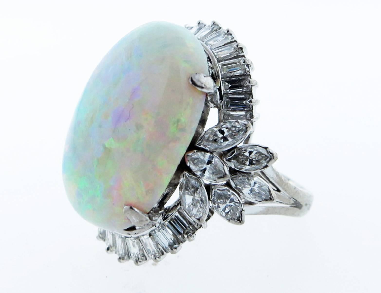 Handmade platinum mount opal and diamond ring. The center is prong set with an oval cabochon opal measuring approx 21.3mm. x 15.1 mm. weighing approx 15.5cts. The surrounding mount is prong set with 26 baguette cut diamonds and 12 marquise cut