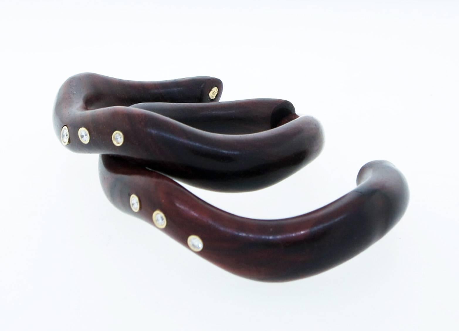 A nestling pair of natural softly polished and beautifully grained rosewood cuff bracelets. Each cuff can be worn separately or together and are bezel set in 18kt. yellow gold with three round brilliant cut diamonds totaling approx .40cts.
The cuffs