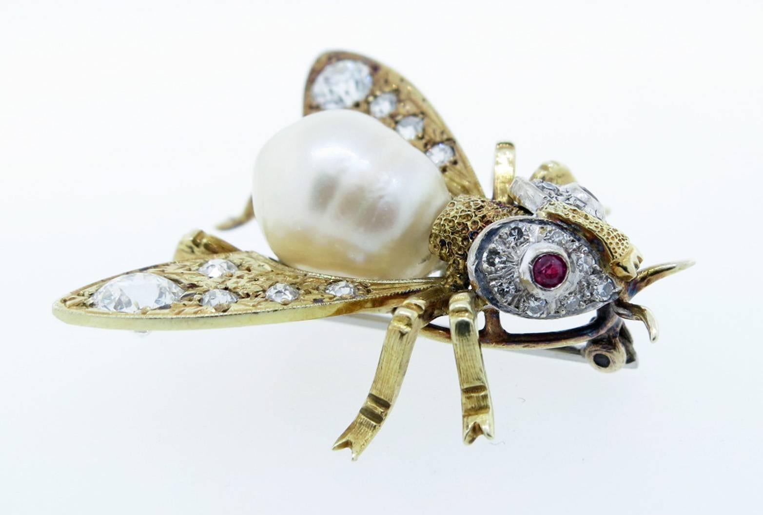 Handmade 18kt. yellow gold fly brooch measuring  1 1/4 inches in length. The baroque pearl body measures approx 10.5mm. The beautifully engraved wings and face are set with approx 1.5cts of European cut diamonds and natural ruby eyes.
