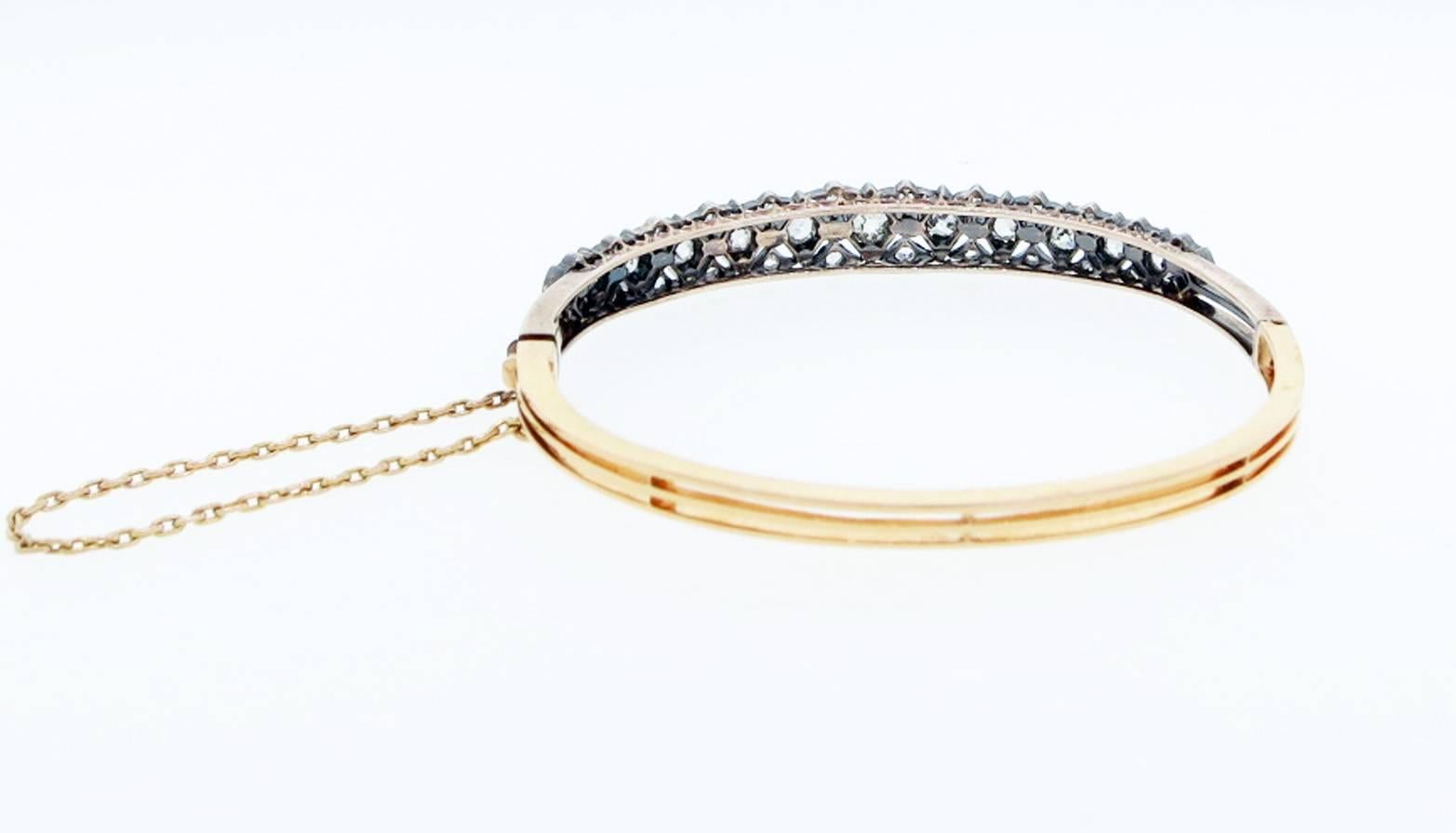 Exquisite antique 18kt. yellow gold silver top bangle bracelet with a very special sparkle that only a genuine antique exhibits. Prong set with graduating old cushion cut diamonds in the center with 54 old rose cut diamonds accents.The bracelet is