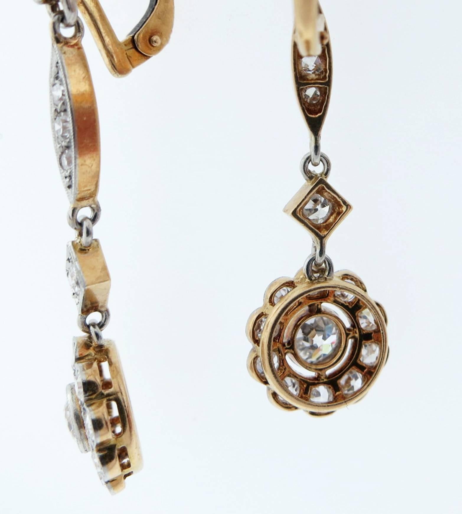 Finely made antique French back platinum top and 18kt. yellow gold back diamond articulated drop earrings. Each earring measures approx 1.75 inches in length and are bead and bezel set in mill grained platinum with 16 old mine and European cut