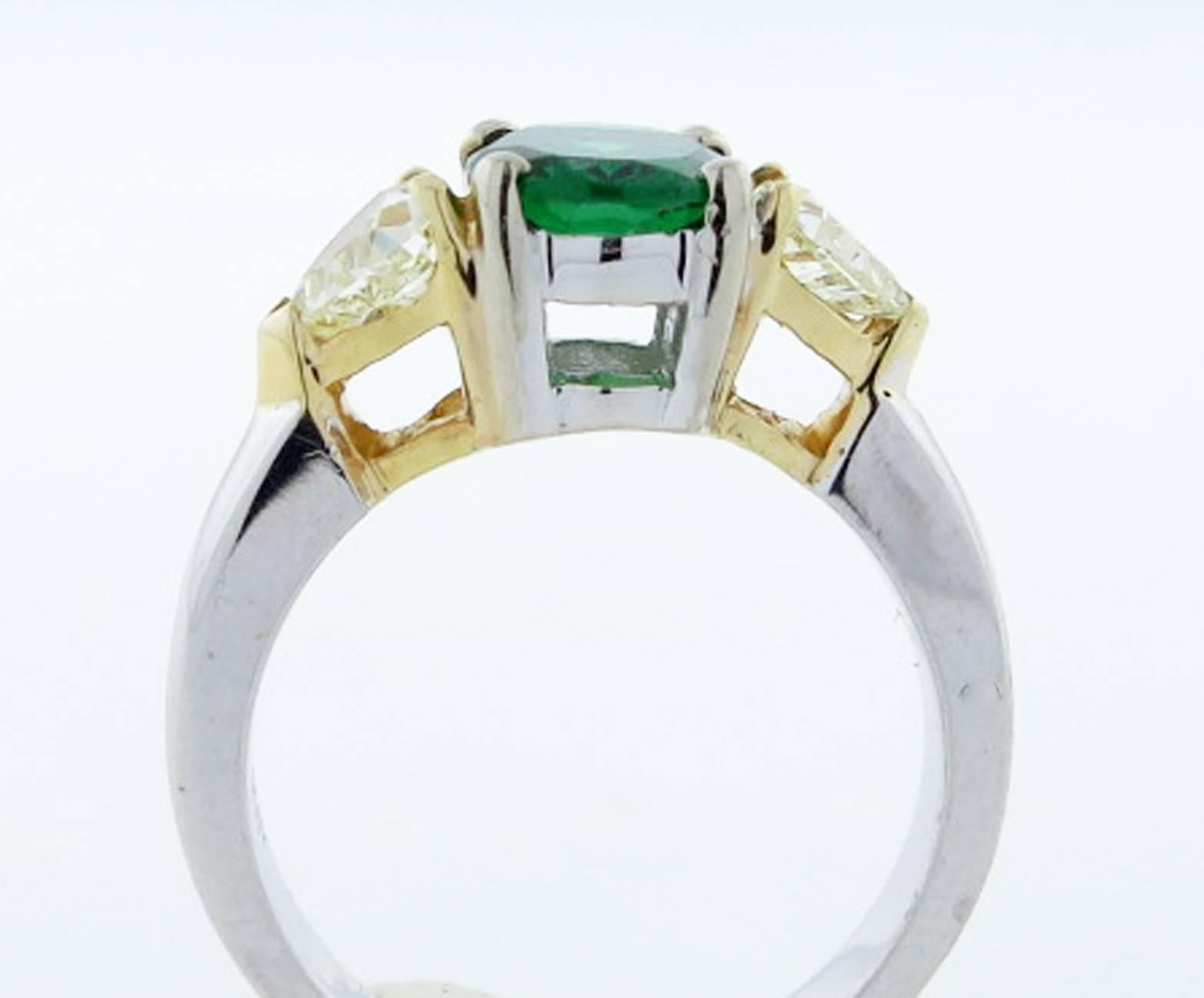 18kt. yellow and white gold Tsavorite garnet and diamond ring. The center is set with a faceted fine oval faceted green garnet (tsavorite) measuring 7.8mm. x 6.2mm. weighing approx 1.2 cts. Each side is set with a heart shape fancy yellow diamond