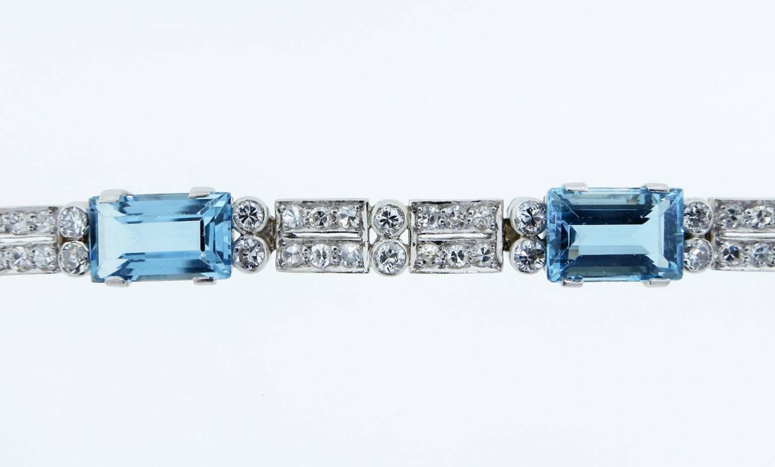 Simple elegant natural aquamarine and diamond bracelet in platinum and 18kt. white gold. The fluid bracelet measures seven inches in length and 1/4 inches in width. Prong set with seven faceted emerald cut sky blue aquamarines each weighing approx
