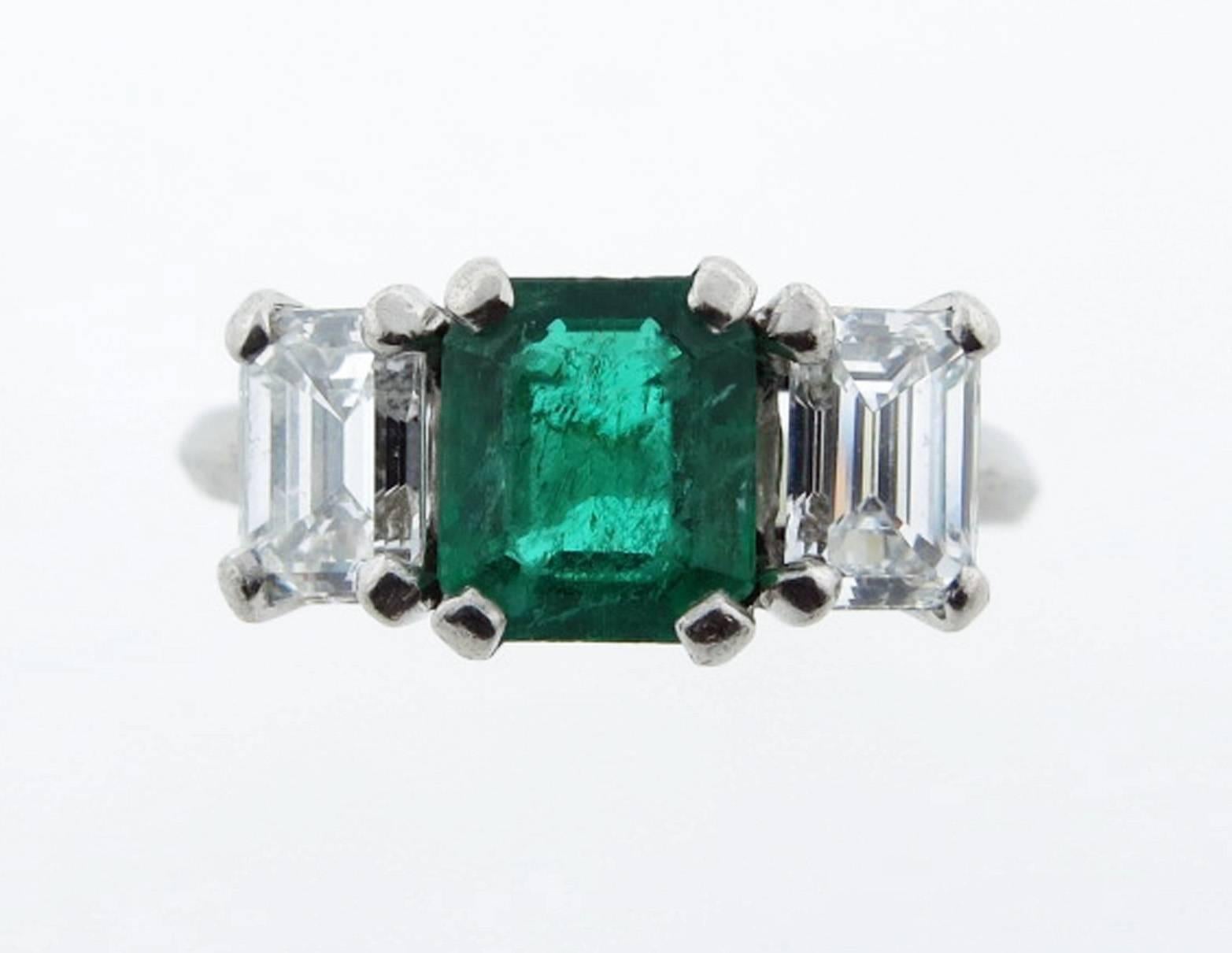 Handmade platinum mount three stone ring. The center is prong set with a natural fine emerald cut emerald measuring 6.7mm. x 6.2mm. weighing approx 1.25cts. Each side is prong set with an emerald cut diamond measuring 5.7mm. x 4.1 mm. weighing