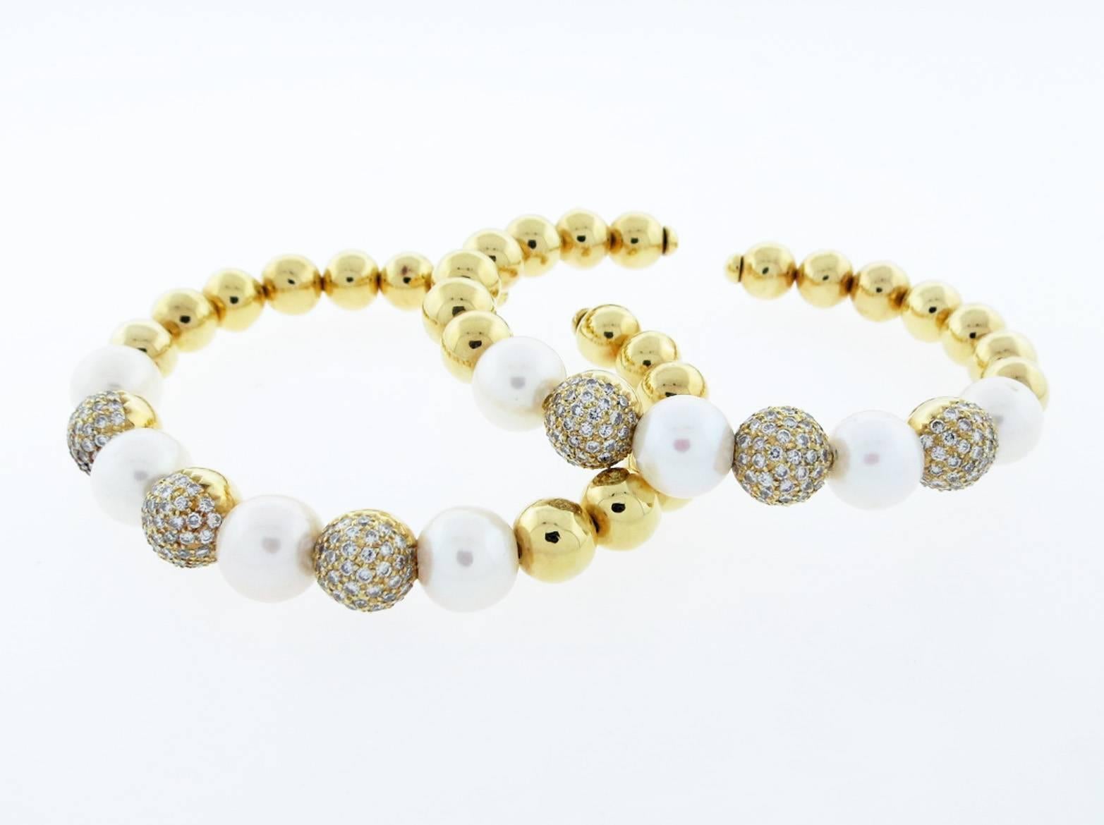  Contemporary pair of 18kt. yellow gold flexible cuff bracelets. Each bracelet is strung with five 10mm. cultured pearls with three alternating diamond pave balls across the top. The diamond balls are bead set with 36 round brilliant cut diamonds.