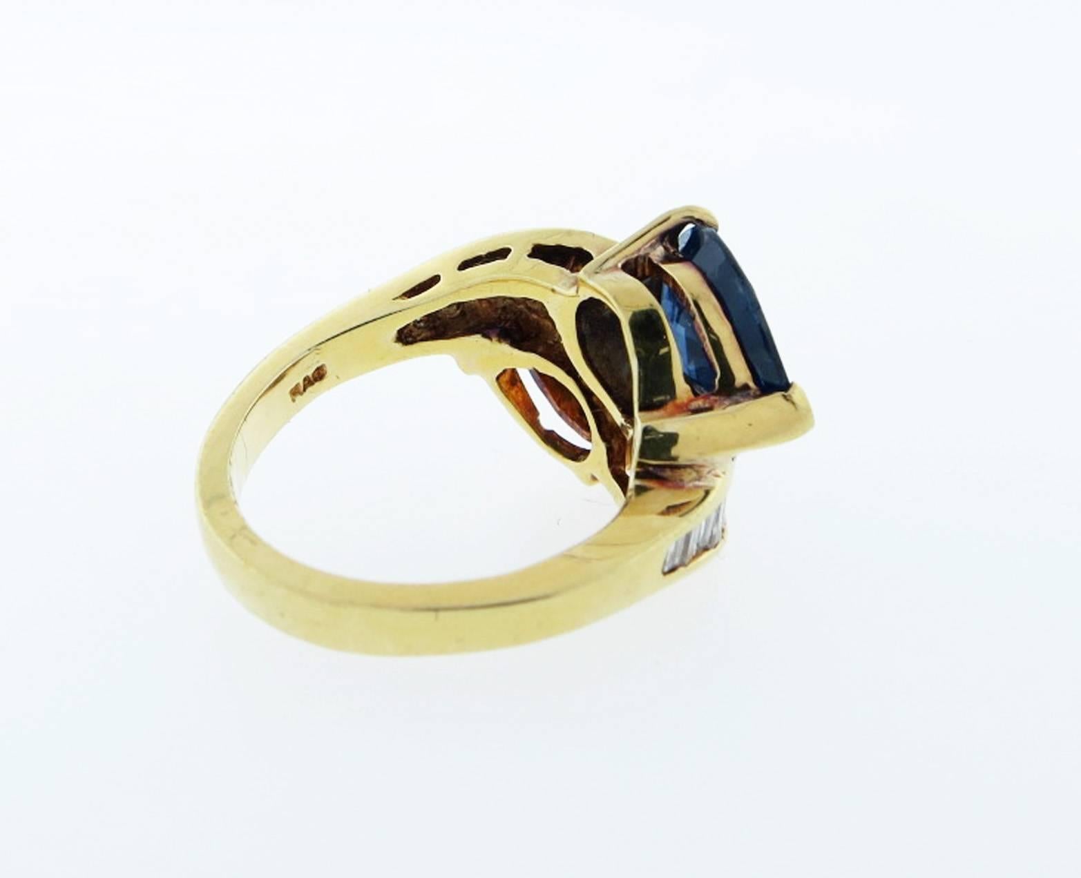 Fine 18kt. yellow gold mounted yellow and blue sapphire ring in a crossover design each sapphire weighs approx 2.25cts. Each shoulders is channel set with nine tapered baguette cut diamonds totaling approx .50cts. The ring is size 6 and can be